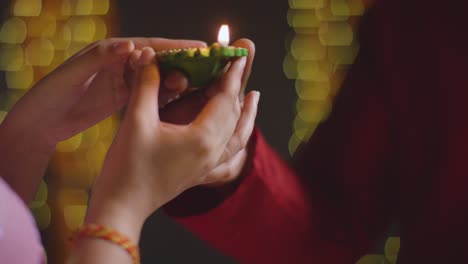 Close-Up-Of-Man-Handing-Lit-Diya-Oil-Lamp-To-Woman-Celebrating-Festival-Of-Diwali